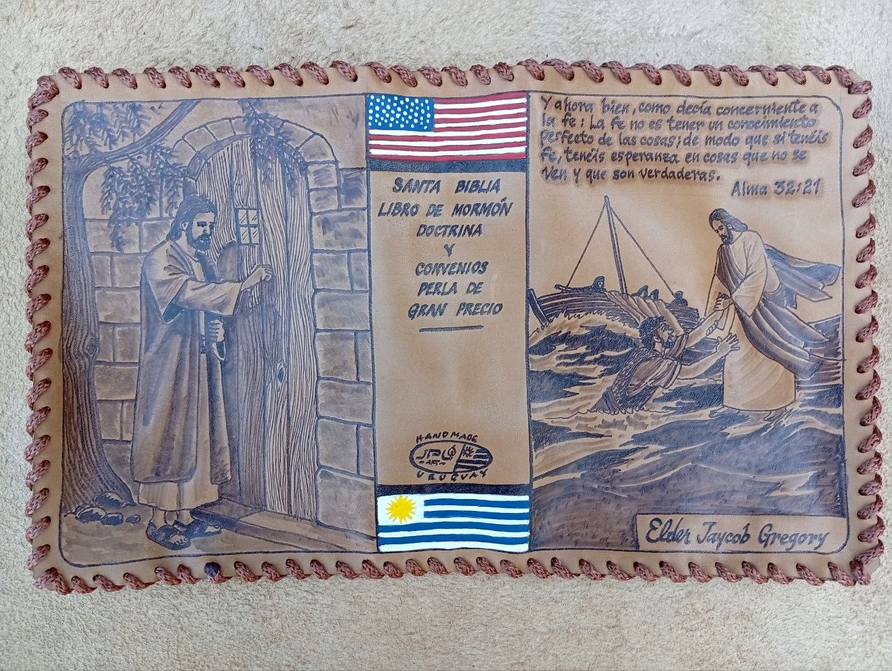 Hand-laced cowhide scripture cover with Christ knocking at a door, Christ lifting a man from the sea, US and Uruguay flags, Alma 32:21, and the name Elder Jaycob Gregory