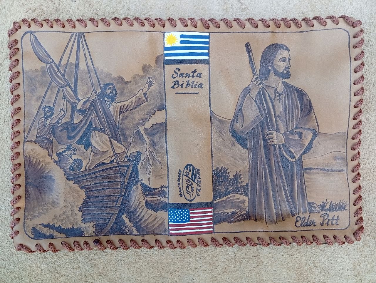 Hand-laced cowhide Santa Biblia cover with pyrography of Christ stilling the storm and Christ with a staff, flags of Uruguay and the United States, and the name Elder Pitt