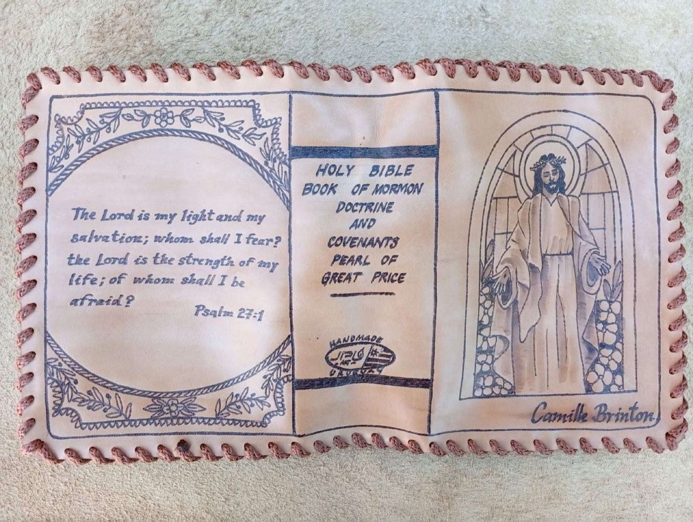 Hand-laced cowhide scripture cover with Psalm 27:1 inside a floral border, Christ standing in an arched doorway, and the name Camille Brinton
