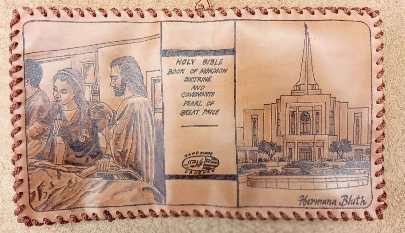 Hand-laced cowhide scripture cover with Christ beside a young woman in medical scrubs, a temple, the standard works on the spine, and the name Hermana Bluth